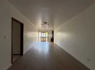 Corredor interno de uma residência com piso de madeira clara e paredes brancas.