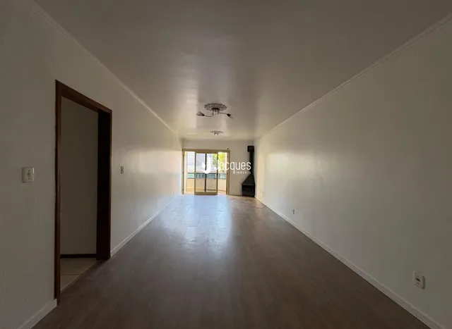 Corredor interno de uma residência com piso de madeira clara e paredes brancas.
