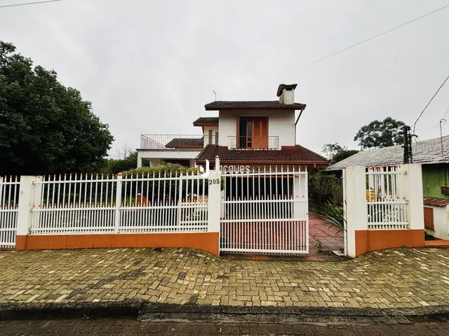 Fachada de uma casa em Lajeado, Brasil, com cerca branca e portão.