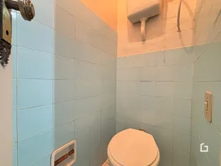 Foto de um banheiro com azulejos azuis claros e vaso sanitário branco.