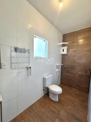 Foto interna de um banheiro com paredes brancas e piso de cerâmica.