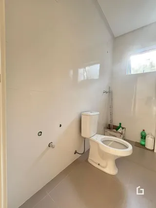 Foto de um banheiro com vaso sanitário branco e paredes brancas.