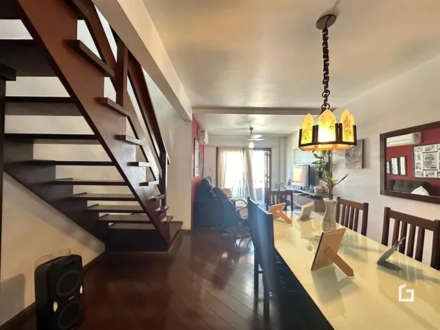 Interior de uma sala de estar com piso de madeira e escadaria em Lajeado.