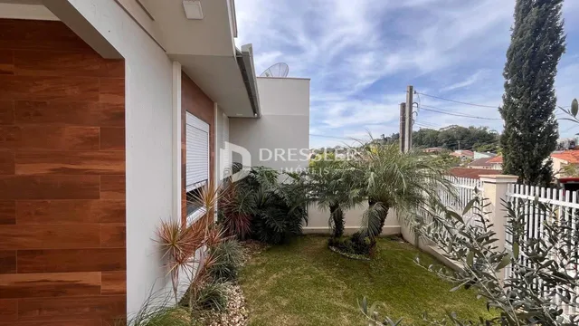 Vista da fachada de uma residência com jardim e cerca no Brasil.