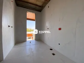Ambiente interno com paredes brancas e piso claro, mostrando um espaço vazio.
