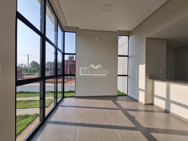 Sala de estar com grandes janelas de vidro que dão vista para o exterior.