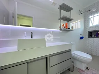 Banheiro moderno com bancada branca e vaso sanitário.