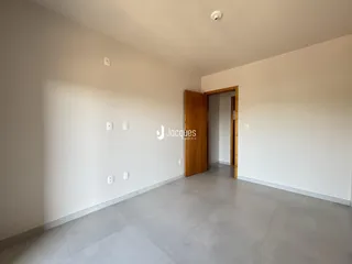 Vista interna de um ambiente com paredes brancas e piso cinza.