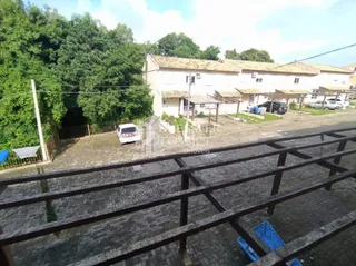 Vista externa de uma propriedade com cerca de madeira no primeiro plano.