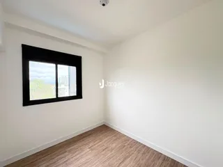 Vista interna de um cômodo com piso de madeira e janela.