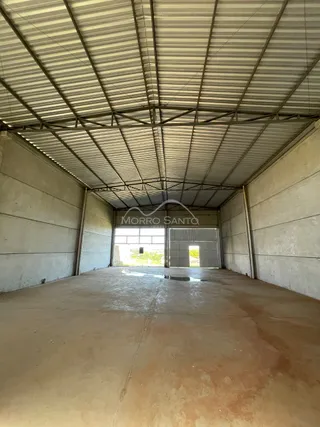 Foto de um espaço interno com piso de concreto e estrutura de teto metálico.