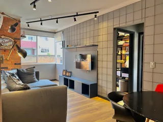 Sala de estar com piso de madeira e parede texturizada em um imóvel no Brasil.