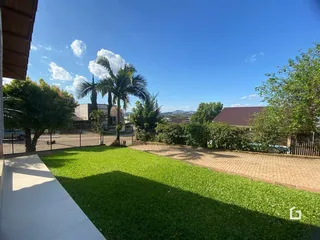 Vista de um jardim gramado com árvores e cerca no fundo da propriedade.