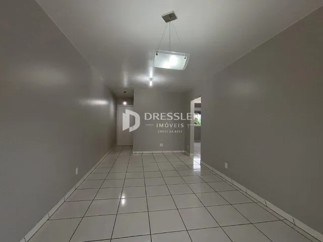 Corredor interno de uma residência com piso de cerâmica branca.