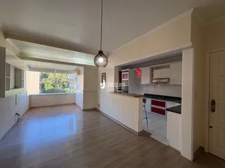 Sala de estar e cozinha integradas com piso de madeira clara.