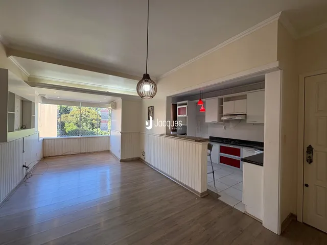Sala de estar e cozinha integradas com piso de madeira clara.