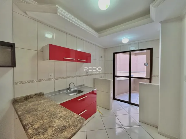 Vista interna de uma cozinha com armários vermelhos e piso de cerâmica.