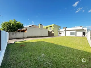 Fachada de uma residência com um grande gramado no quintal em Lajeado.