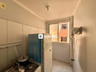 Foto de um ambiente interno mostrando uma área de preparo com fogão e armários brancos.