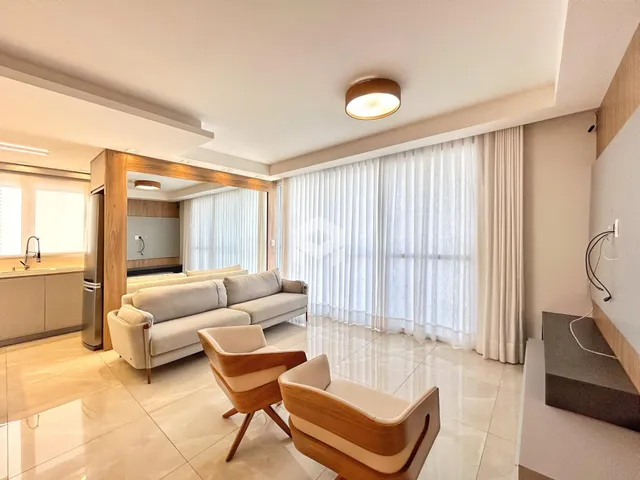Sala de estar com piso de porcelanato claro e grandes janelas.