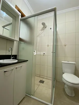 Foto de um banheiro com box de vidro e revestimento branco.