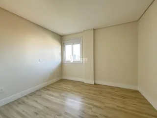 Ambiente interno com piso de madeira clara e parede branca.