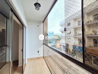 Sala de estar com piso de madeira e vista para edifícios urbanos.