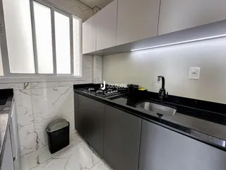 Cozinha moderna com armários brancos e bancadas escuras.