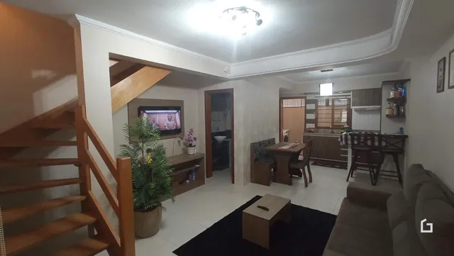 Interior de uma sala com escadaria de madeira e sofá.
