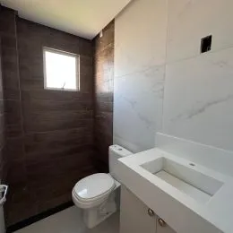 Foto de um banheiro com vaso sanitário e bancada branca.