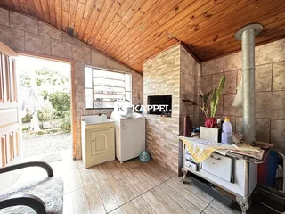 Uma foto interna mostra uma área de cozinha com piso de madeira e paredes de azulejo.