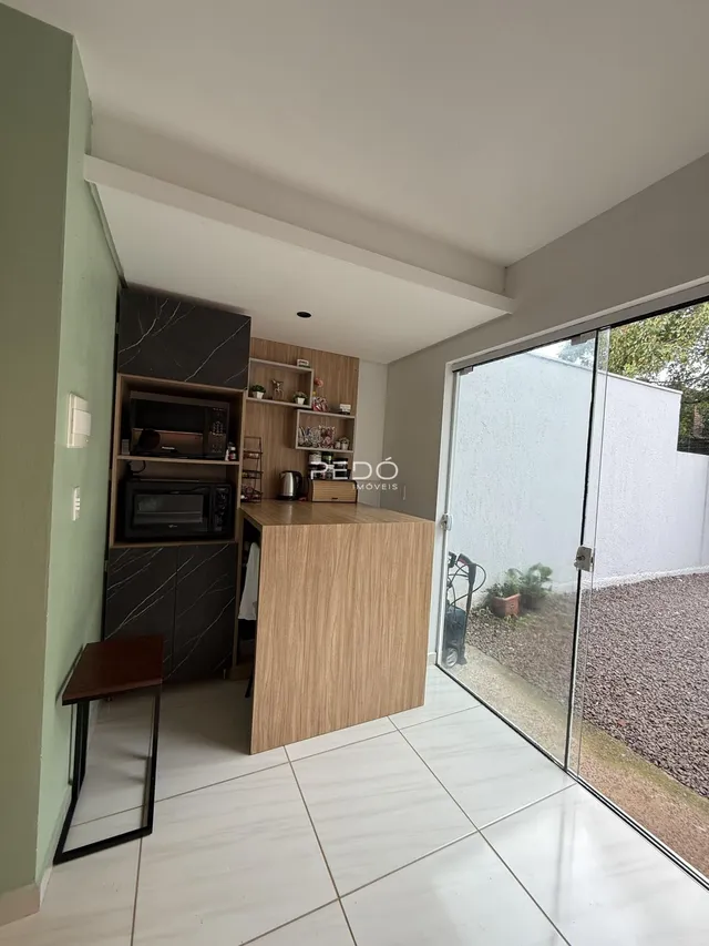 Ambiente interno de sala de estar com cozinha integrada e porta de vidro para o quintal.