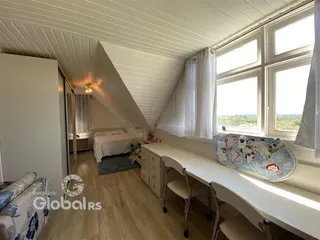Quarto com teto inclinado e grandes janelas em um imóvel em Lajeado.