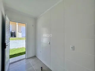 Corredor com paredes brancas e piso de cerâmica claro.