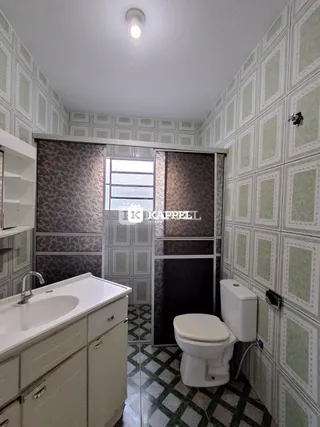 Banheiro com pia branca e vaso sanitário em parede decorada com padrão geométrico.
