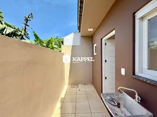 Vista de um corredor externo com piso de cerâmica e uma pia na parede.