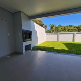 Foto de uma área externa pavimentada com parede branca e vista para a vegetação.