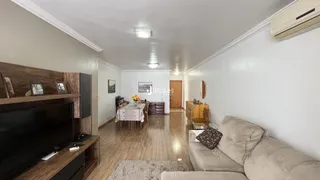 Sala de estar com piso de madeira e sofá claro.