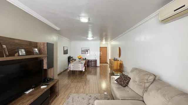Sala de estar com piso de madeira e sofá claro.