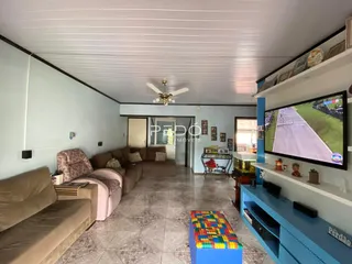 Sala de estar ampla com sofá e televisão em um imóvel no Brasil.