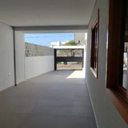Corredor interno com piso claro e paredes brancas.