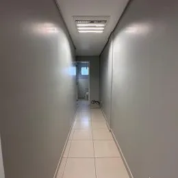 Corredor interno com paredes brancas e piso claro.