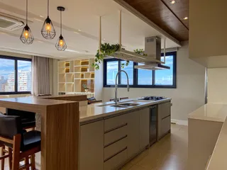 Cozinha moderna com ilha de madeira e bancada clara em um apartamento em Lajeado.