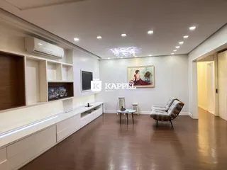 Sala de estar com painéis brancos, televisão e piso de madeira.