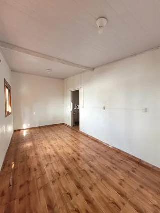 A foto mostra um ambiente com piso de madeira e paredes brancas.