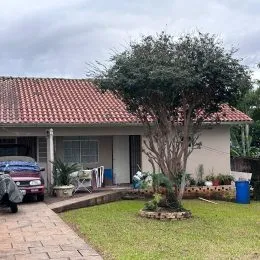 Vista externa de uma casa com telhado e gramado verde.