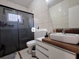 Foto de um banheiro com bancada de madeira e box de vidro.