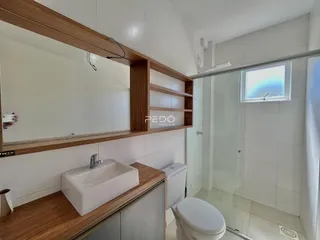 Banheiro com revestimento branco e bancada de madeira.