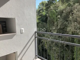 Vista da fachada de um imóvel com grade de segurança e vegetação densa ao fundo.