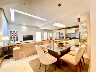 Sala de estar e jantar moderna com decoração clara e móveis de madeira.